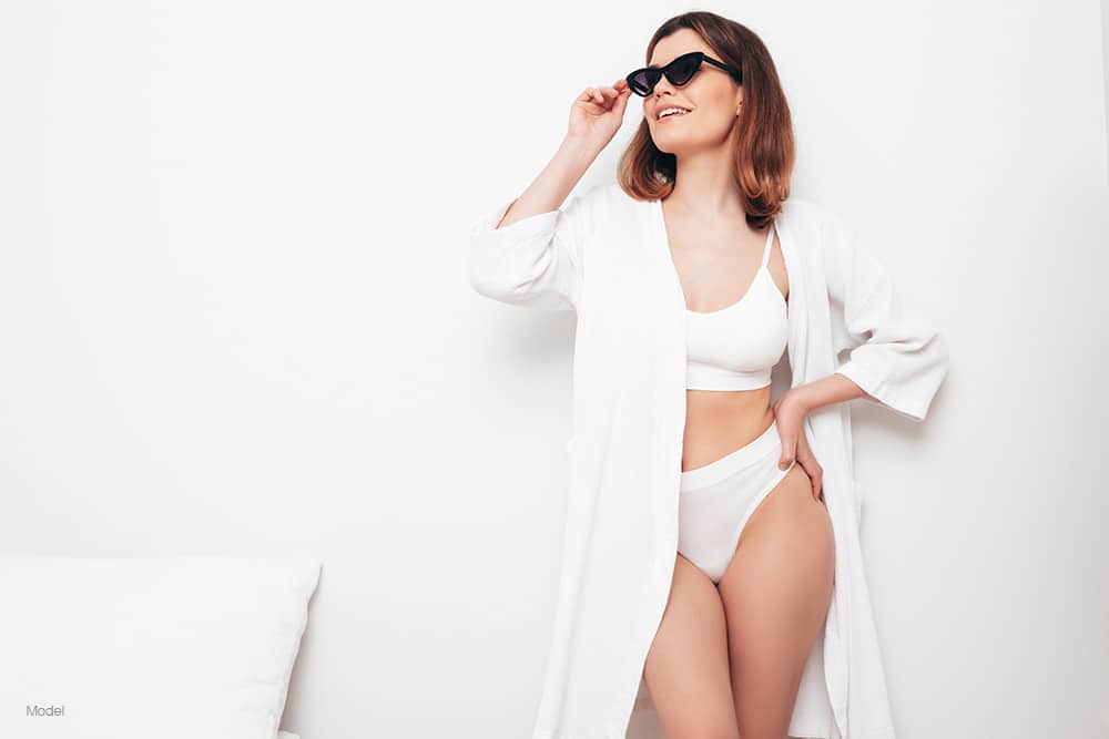 Curvy woman in white robe wearing black sunglasses